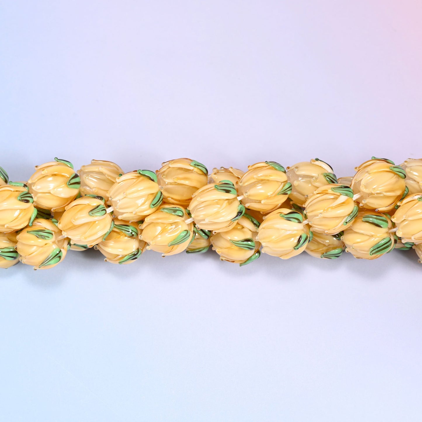 Creamy yellow tulip bud-shaped lampwork glass beads, hand-formed with sculpted petal detailing that gives a realistic flower bud look, accented with a green leaf detail at the base.
