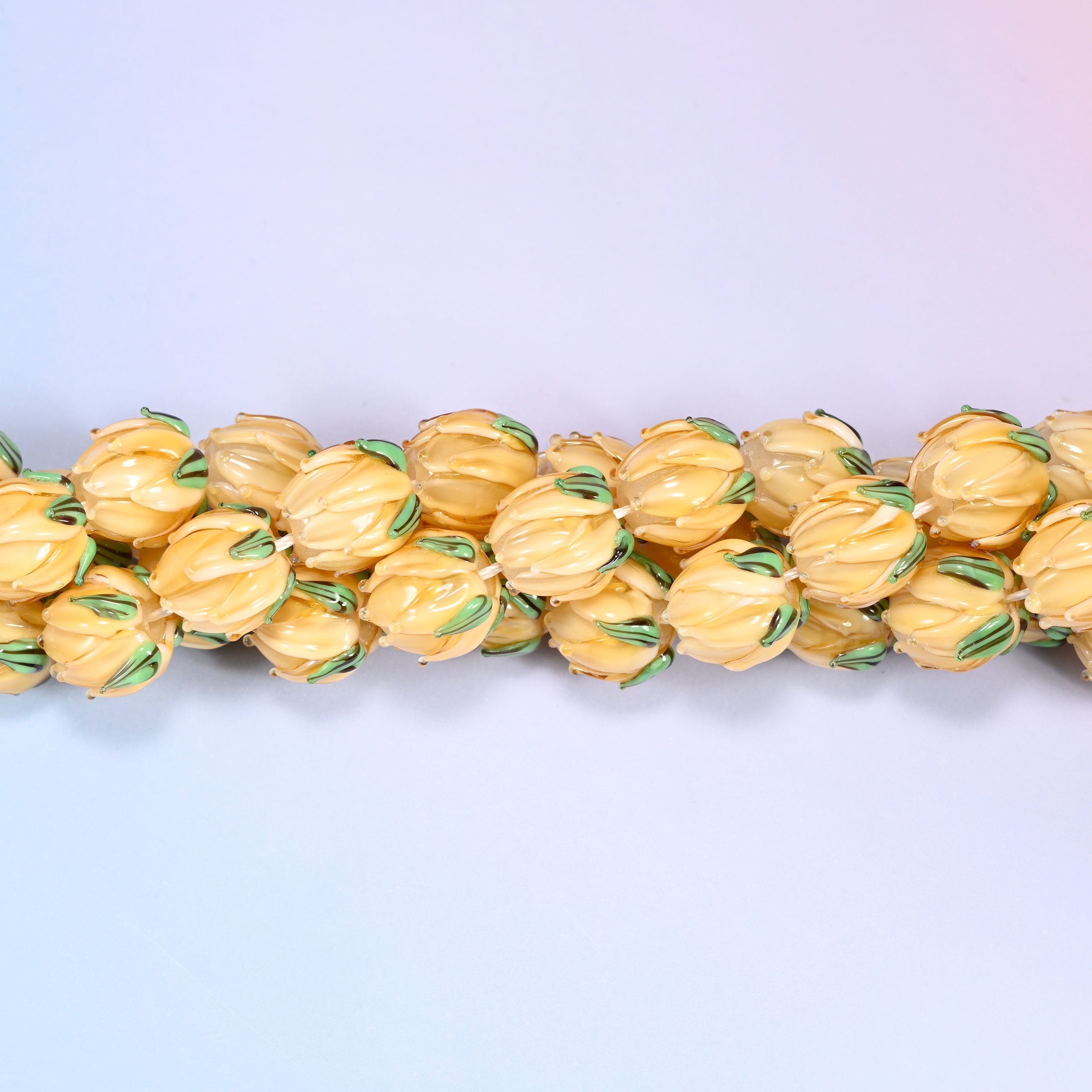 Creamy yellow tulip bud-shaped lampwork glass beads, hand-formed with sculpted petal detailing that gives a realistic flower bud look, accented with a green leaf detail at the base.