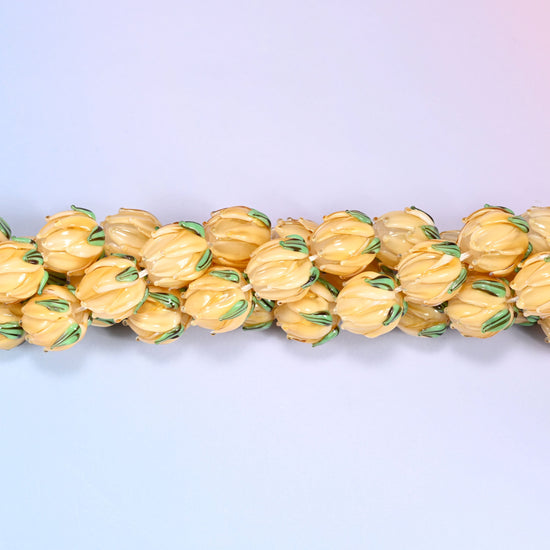 Creamy yellow tulip bud-shaped lampwork glass beads, hand-formed with sculpted petal detailing that gives a realistic flower bud look, accented with a green leaf detail at the base.