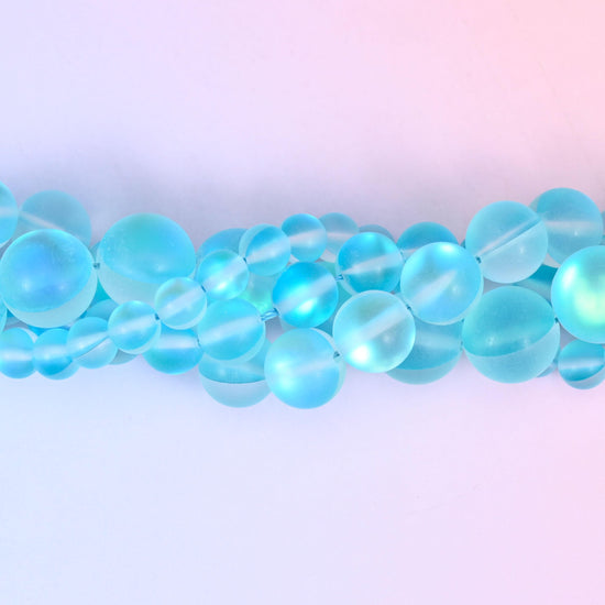 Bright aqua glass beads with a sanded frosted finish and aurora glow