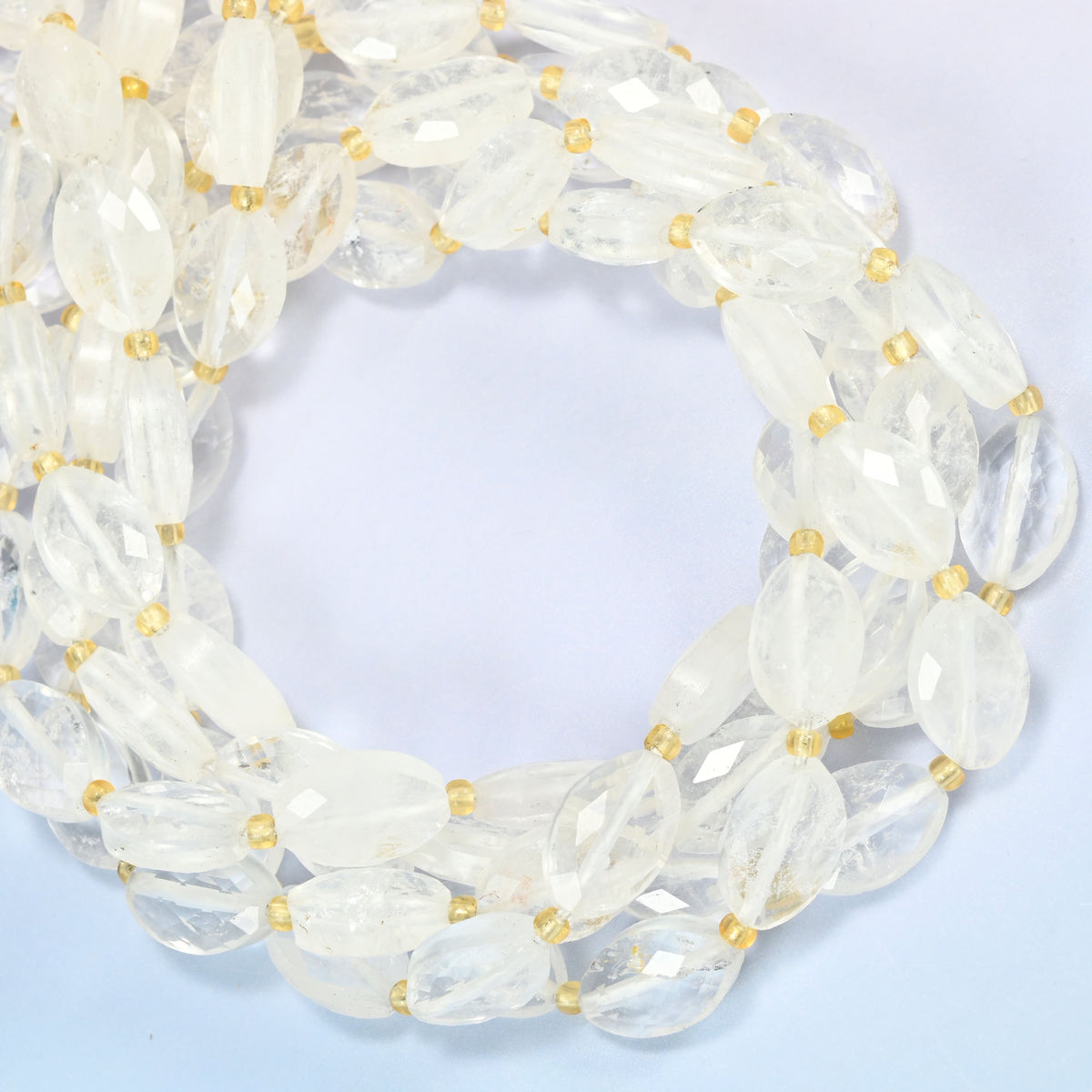 Clear quartz faceted flat oval beads coiled into overlapping loops, whole strands of clear sparkling stone