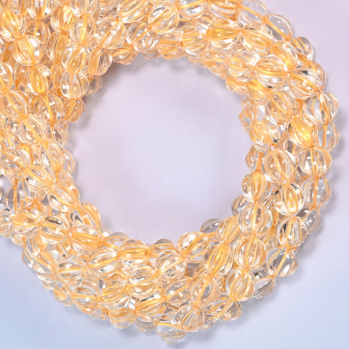 Clear gold pumpkin glass beads coiled with the open center to one side, showing the fluted grooves end on.