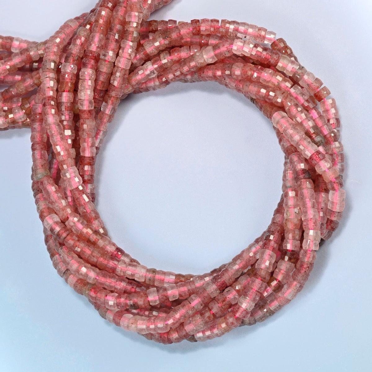 Strawberry quartz faceted heishi disc beads coiled into overlapping loops, whole strands of sparkly pink stone