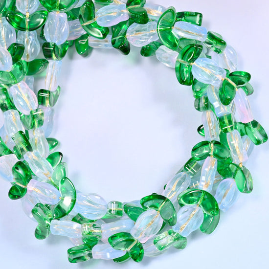 Wide circular coil of white tulip and green leaf glass beads on a lavender and pink gradient background, showing the full wreath.