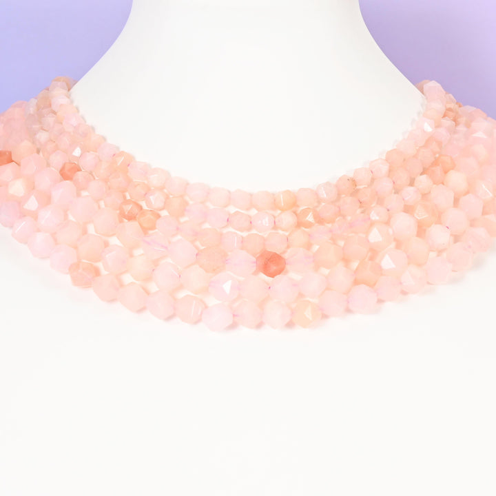Pink Aventurine star cut beads looped around a white neck form, several strands sitting together as a collar