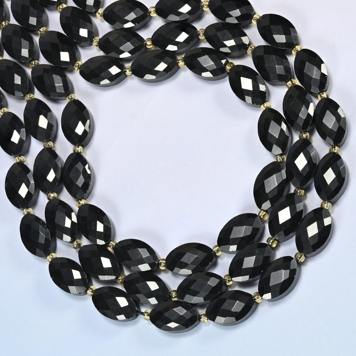 Black onyx faceted flat oval beads curved into an open loop, glossy black beads