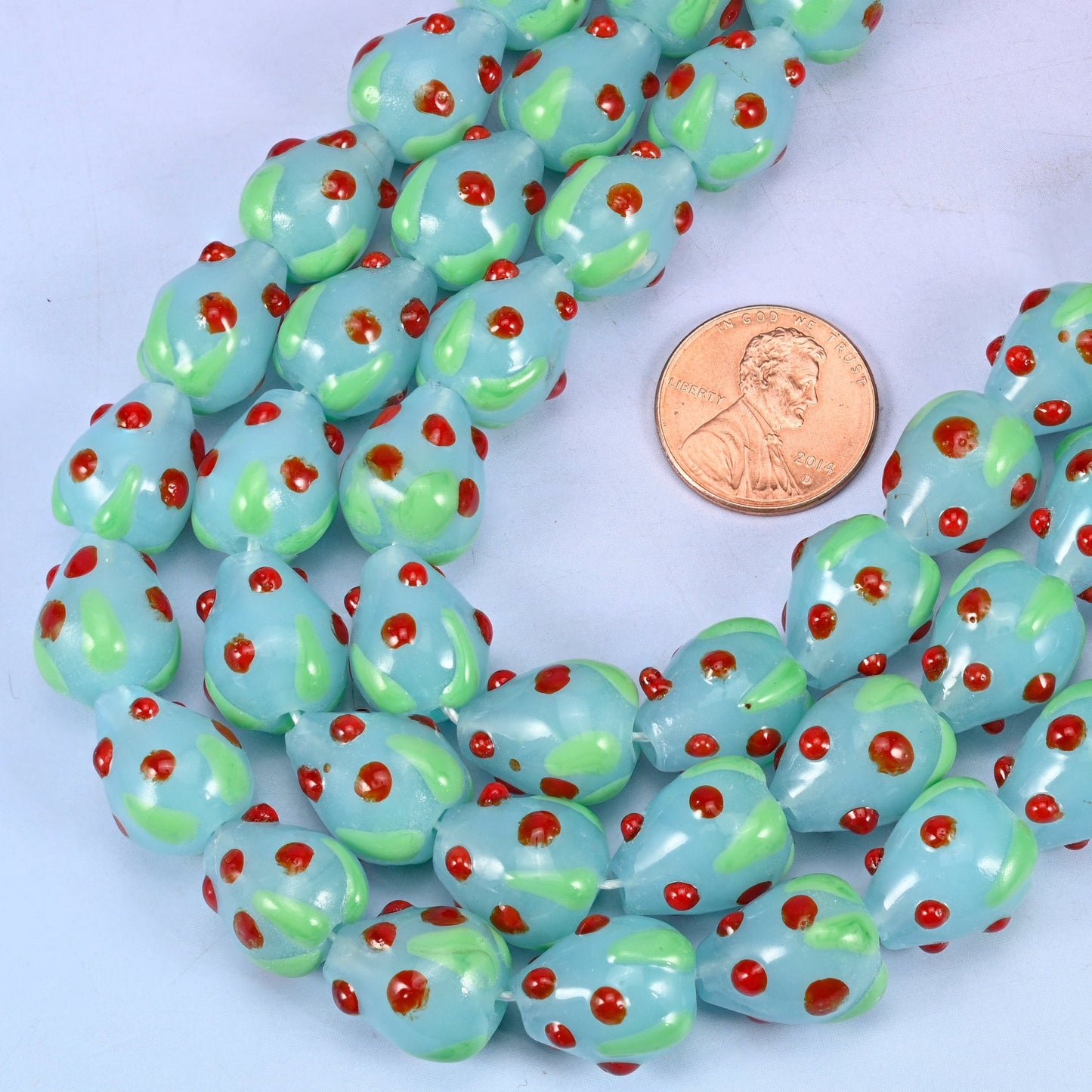 Strawberry shaped glass beads with a scatter of small red seed dots