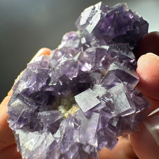 Close view of the crystal field, translucent lilac cubes sitting over darker purple ones behind