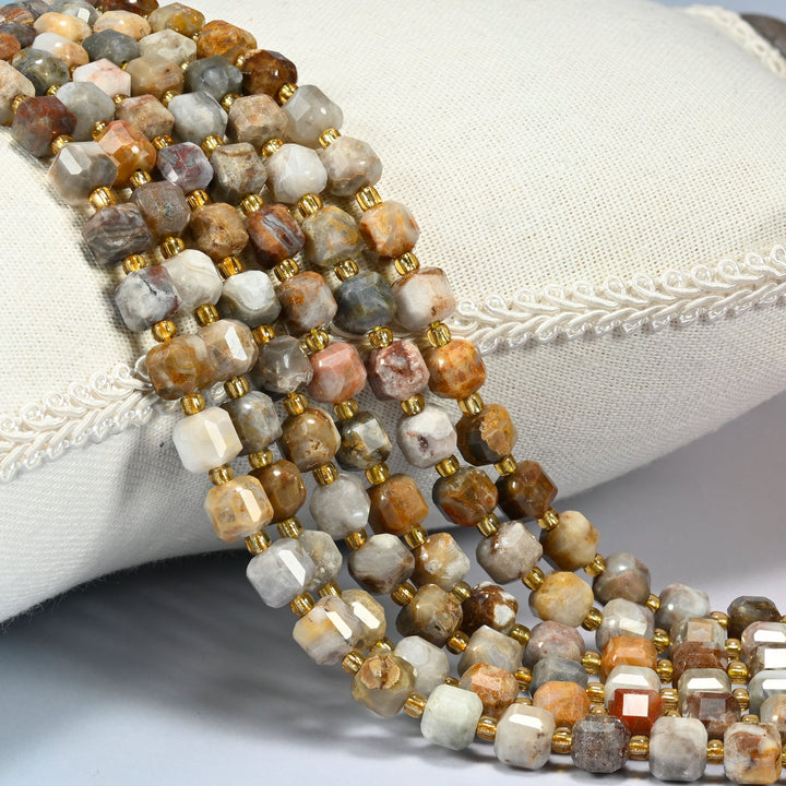 Gobi desert agate faceted cube beads 6mm lying across a white cushion with braided edging.
