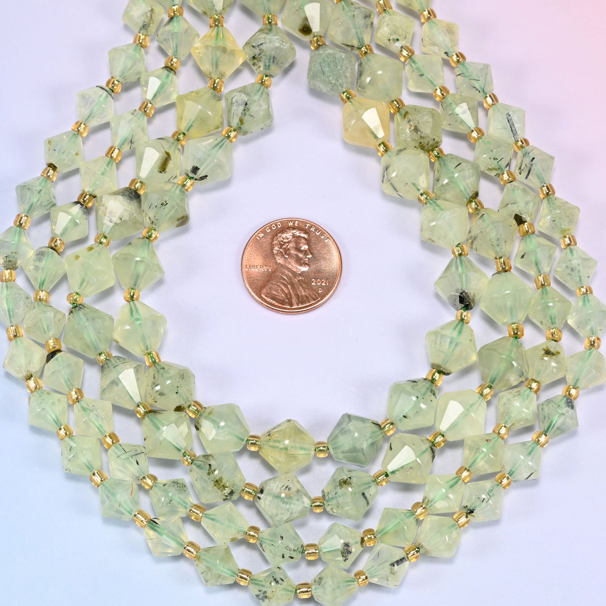 Close-up of Green Prehnite faceted bicone beads, 8mm and 10mm, coiled into a circle, showing the light green color and natural inclusions.
