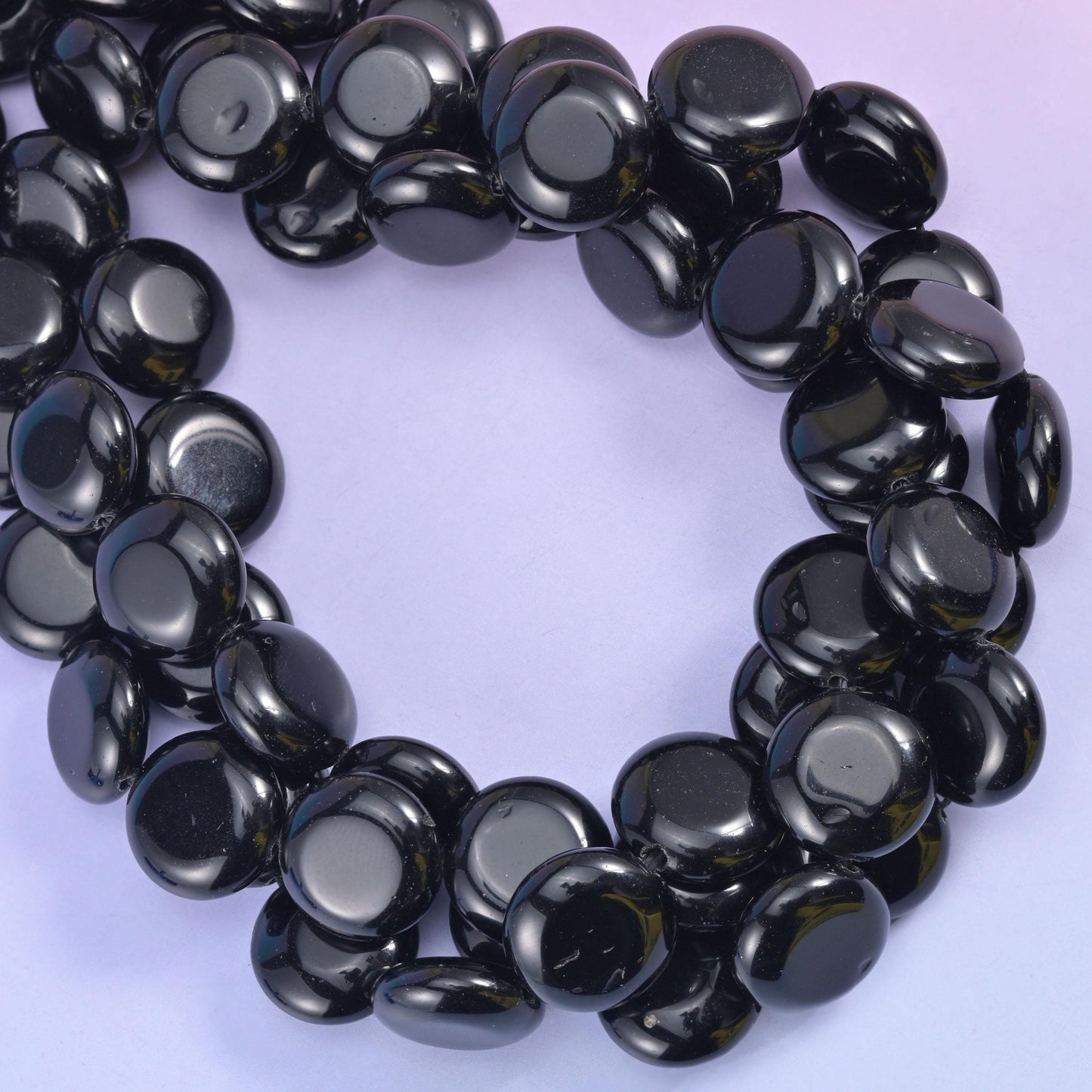 Tight loop of obsidian discs, light sweeping a white streak across every domed face