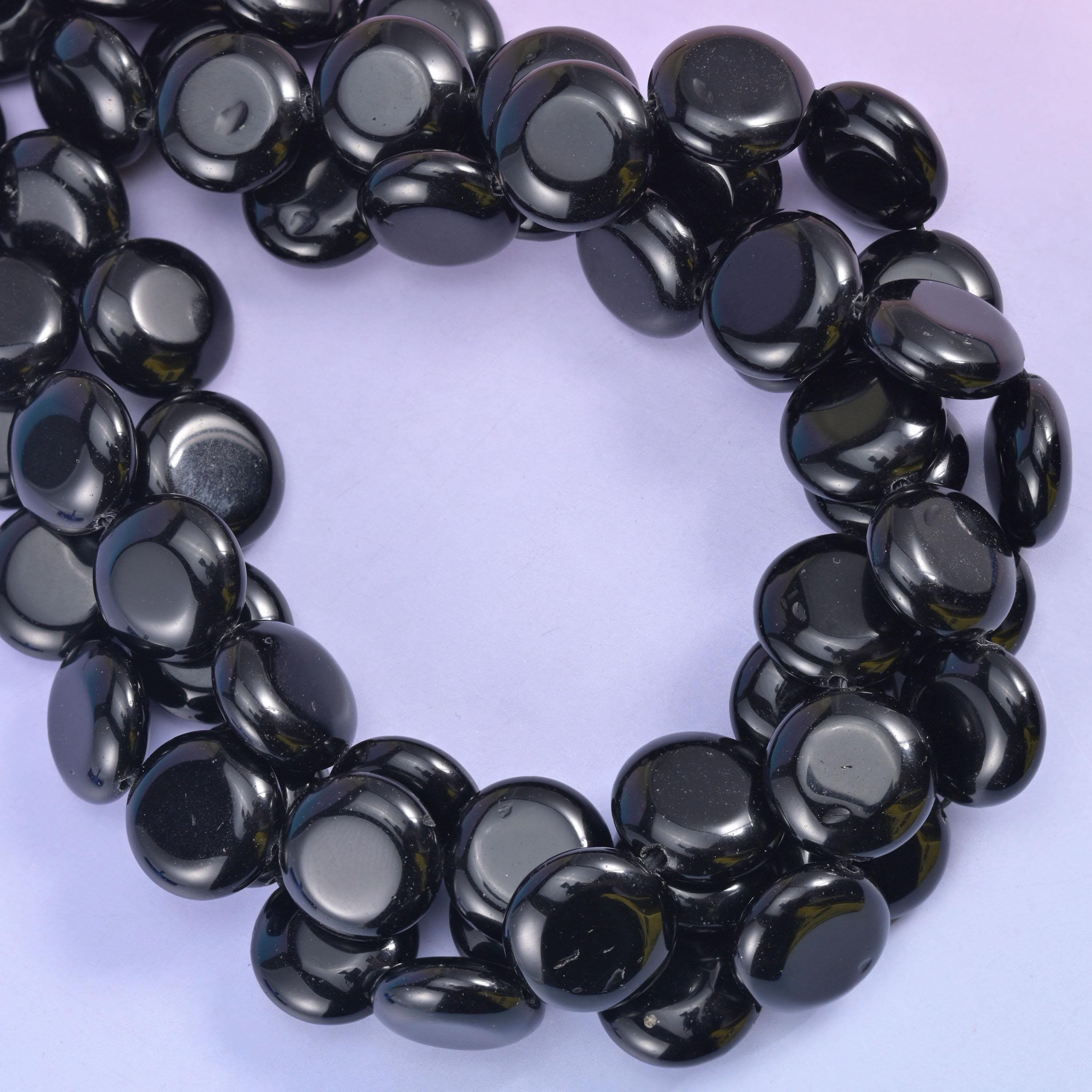 Tight loop of obsidian discs, light sweeping a white streak across every domed face