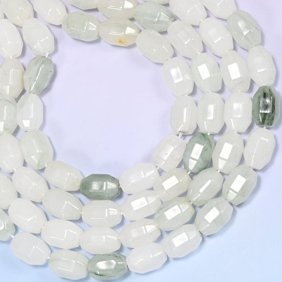 Close-up of a circular coil of Tianshan Jade faceted barrel beads on a light lavender background