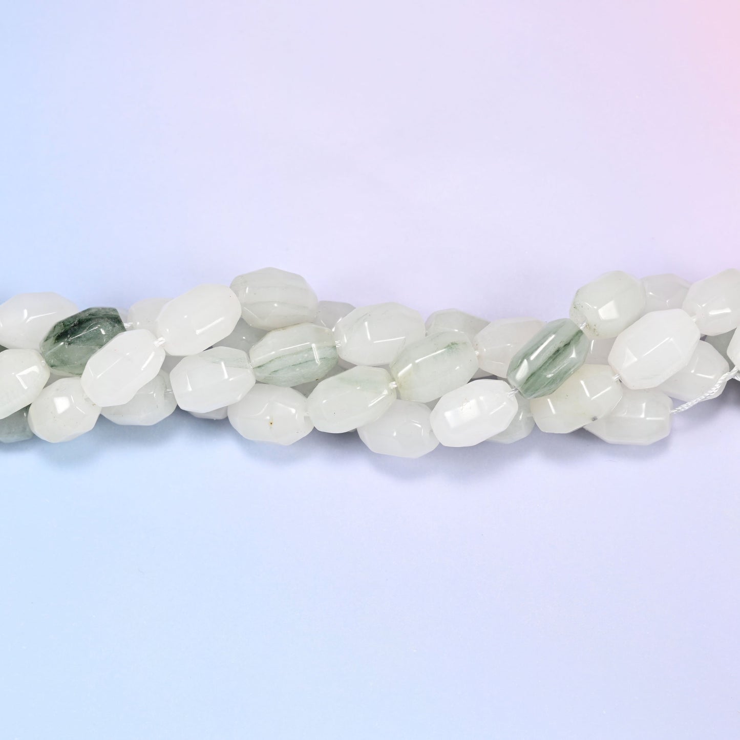Close-up horizontal row of Tianshan Jade faceted barrel beads laid straight, showing the polished facet detail up close.