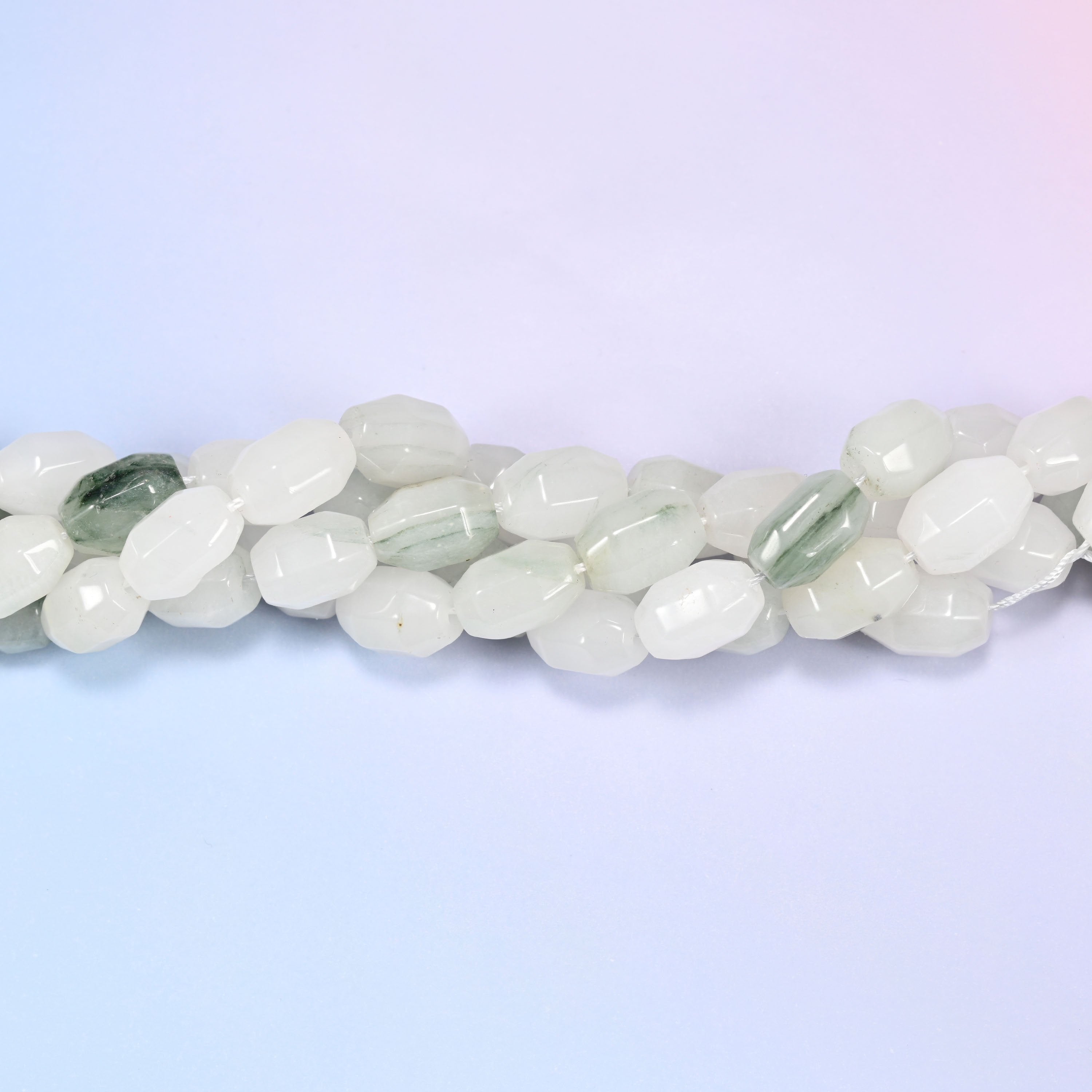 Close-up horizontal row of Tianshan Jade faceted barrel beads laid straight, showing the polished facet detail up close.