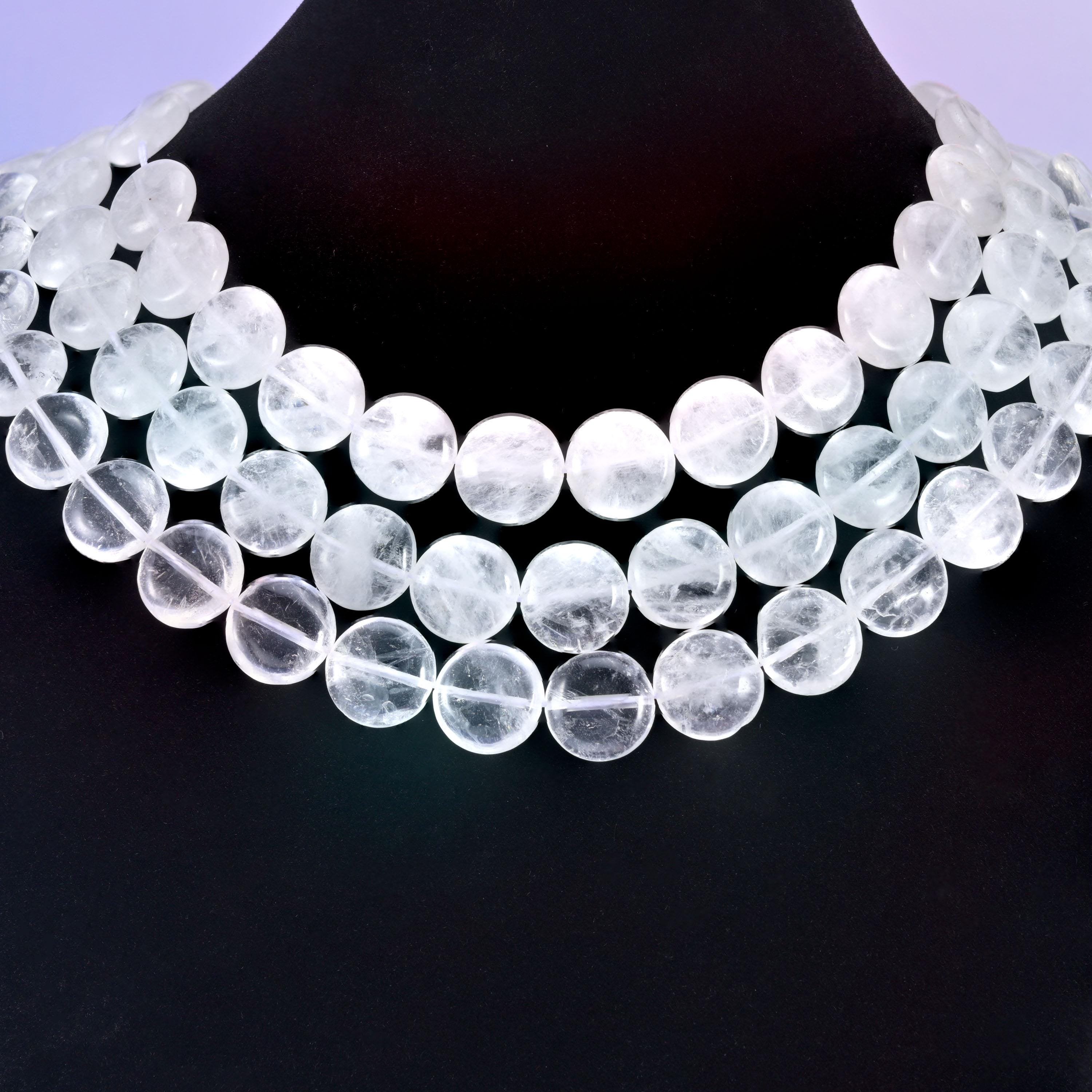 Three-strand clear quartz coin necklace on a black display bust, the 15mm discs glowing bright white