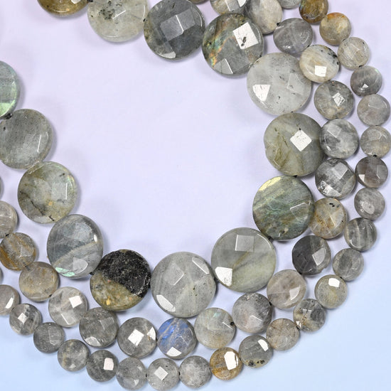 Gray Labradorite faceted coin beads curved into a deep open loop, a near-black disc sitting among the light gray ones