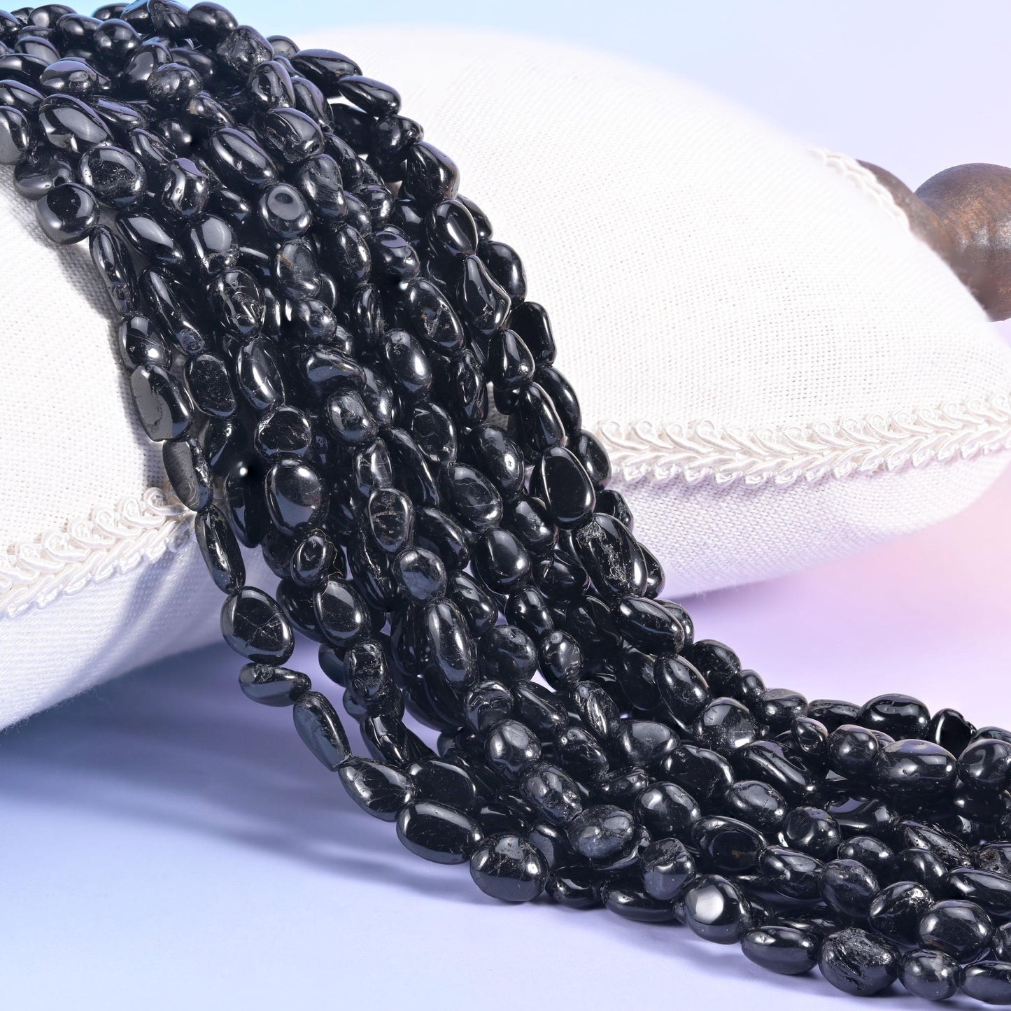 Jet black tourmaline nugget strands draped over a white cushion