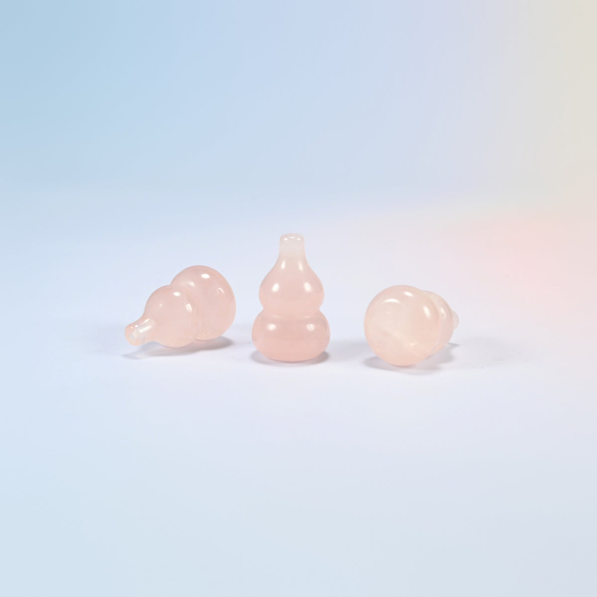Natural rose quartz gourd carvings, one standing and two lying on their sides