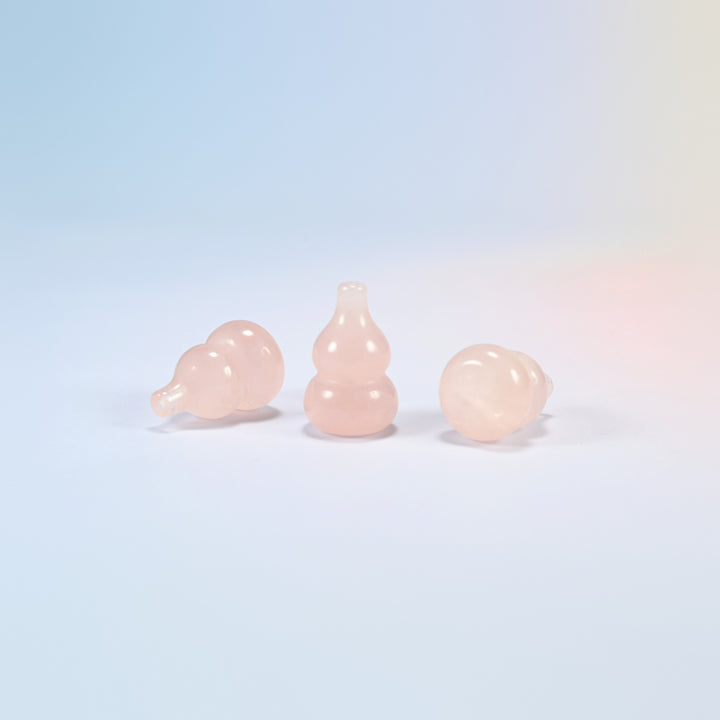 Natural rose quartz gourd carvings, one standing and two lying on their sides