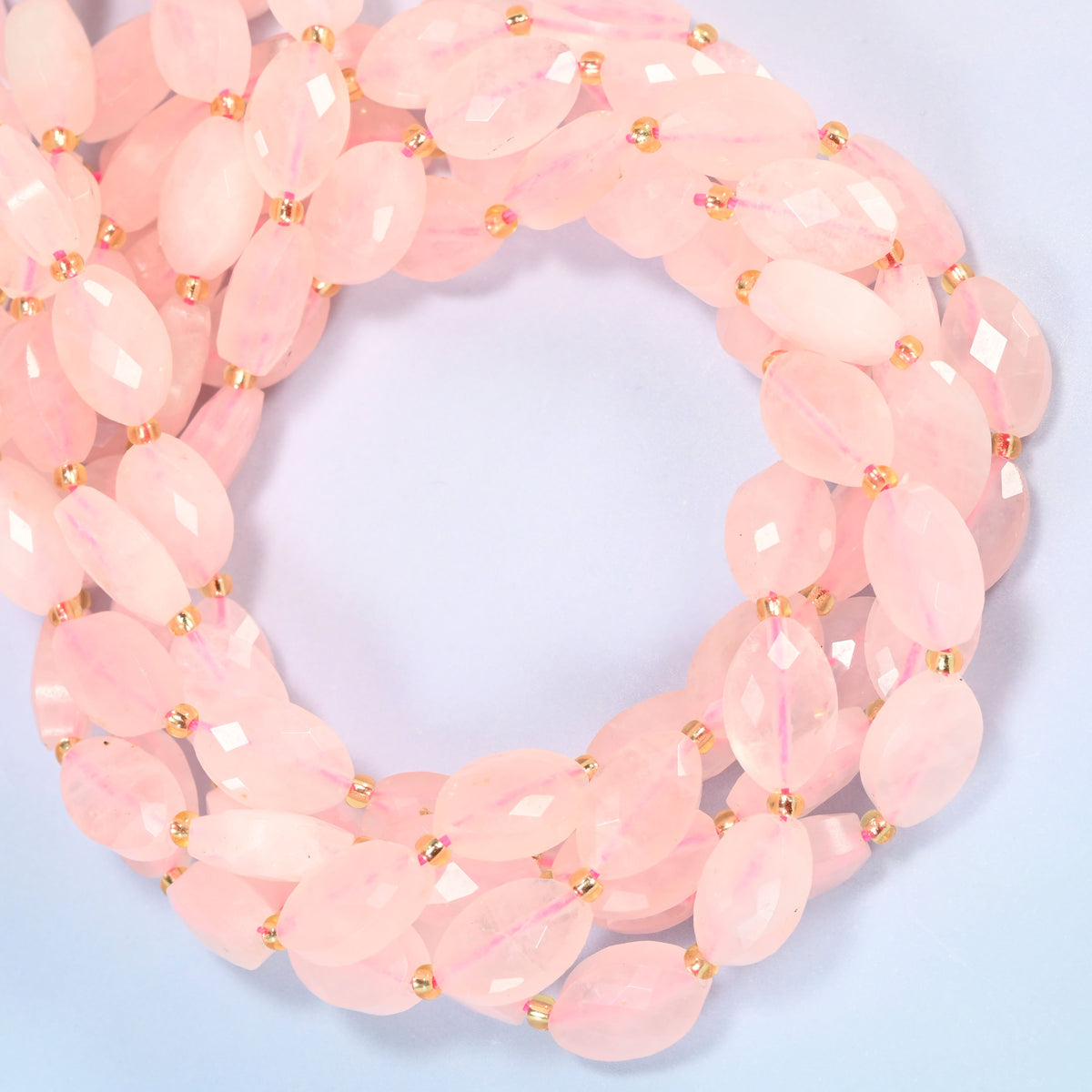 Rose quartz faceted flat oval beads coiled into overlapping loops, whole strands of soft pink stone