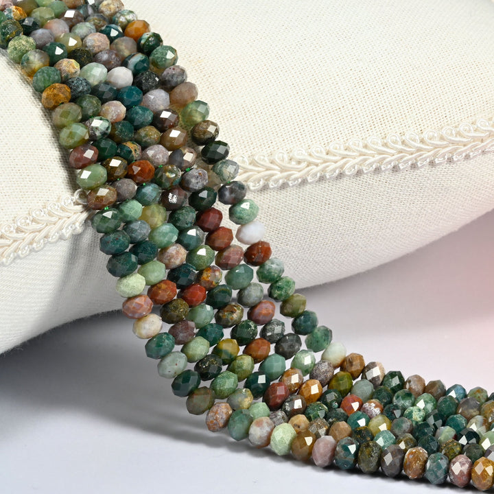 Indian Agate gemstone rondelle beads 4x6mm faceted, strand draped over a cream fabric cushion