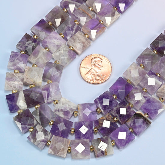 Close view of natural amethyst faceted flat square strands curving beside a US penny for scale