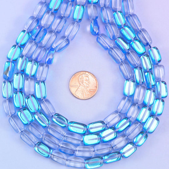 Sapphire blue rectangles in glossy transparent glass, coated in Mystic Aura so a soft iridescent film sits over the deep blue. Cut flat on every side and drilled through the length for easy stringing.