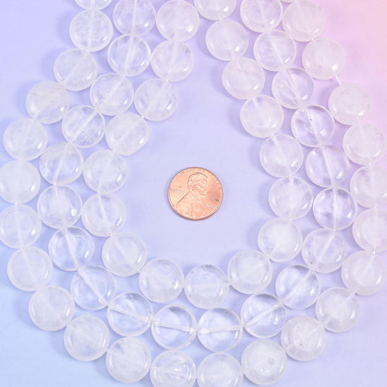Overhead loop of quartz coin beads around a penny on a pink-lilac gradient
