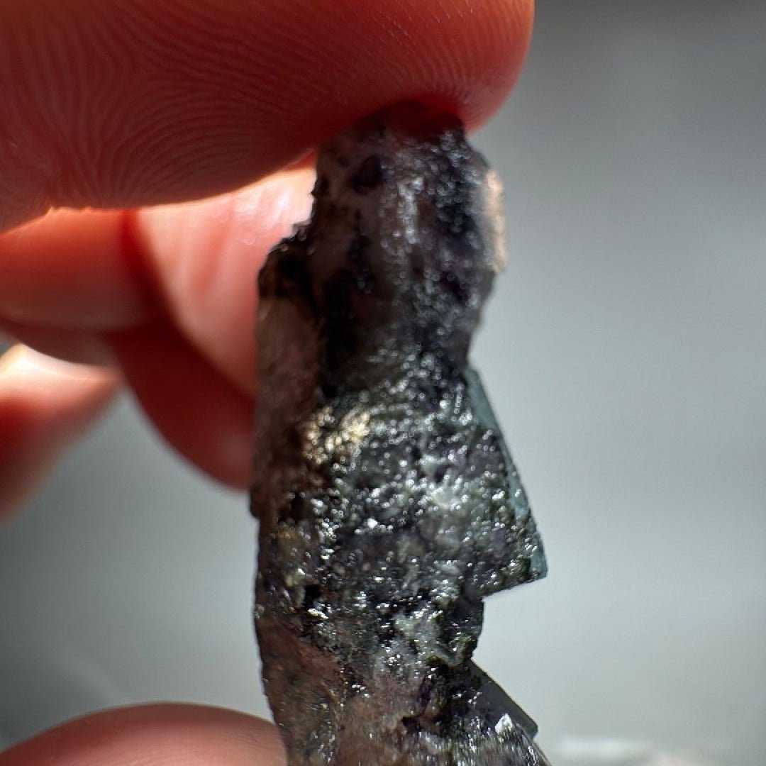 Close view of the crystal tip, frosted white flecks scattered over the dark fluorite