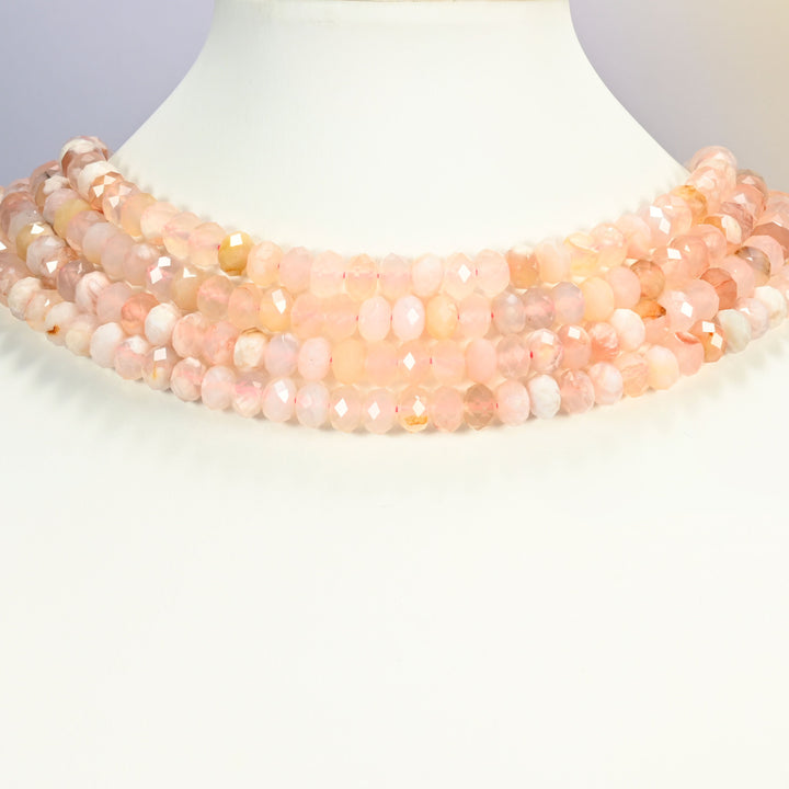 Sakura flower agate faceted rondelle strands arranged as a layered collar on a white display bust, soft pink and cream tones