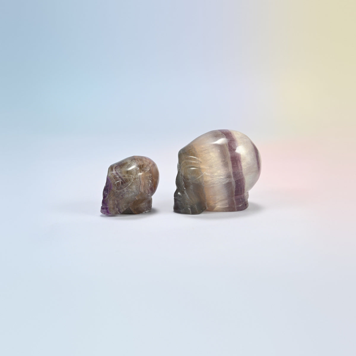 Two fluorite alien head crystal carvings, 1.5 inch and 2 inch, banded purple, green and clear natural stone
