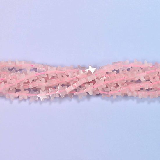 Rose quartz flat star beads in pale milky blush, cut into little flat five-pointed stars.