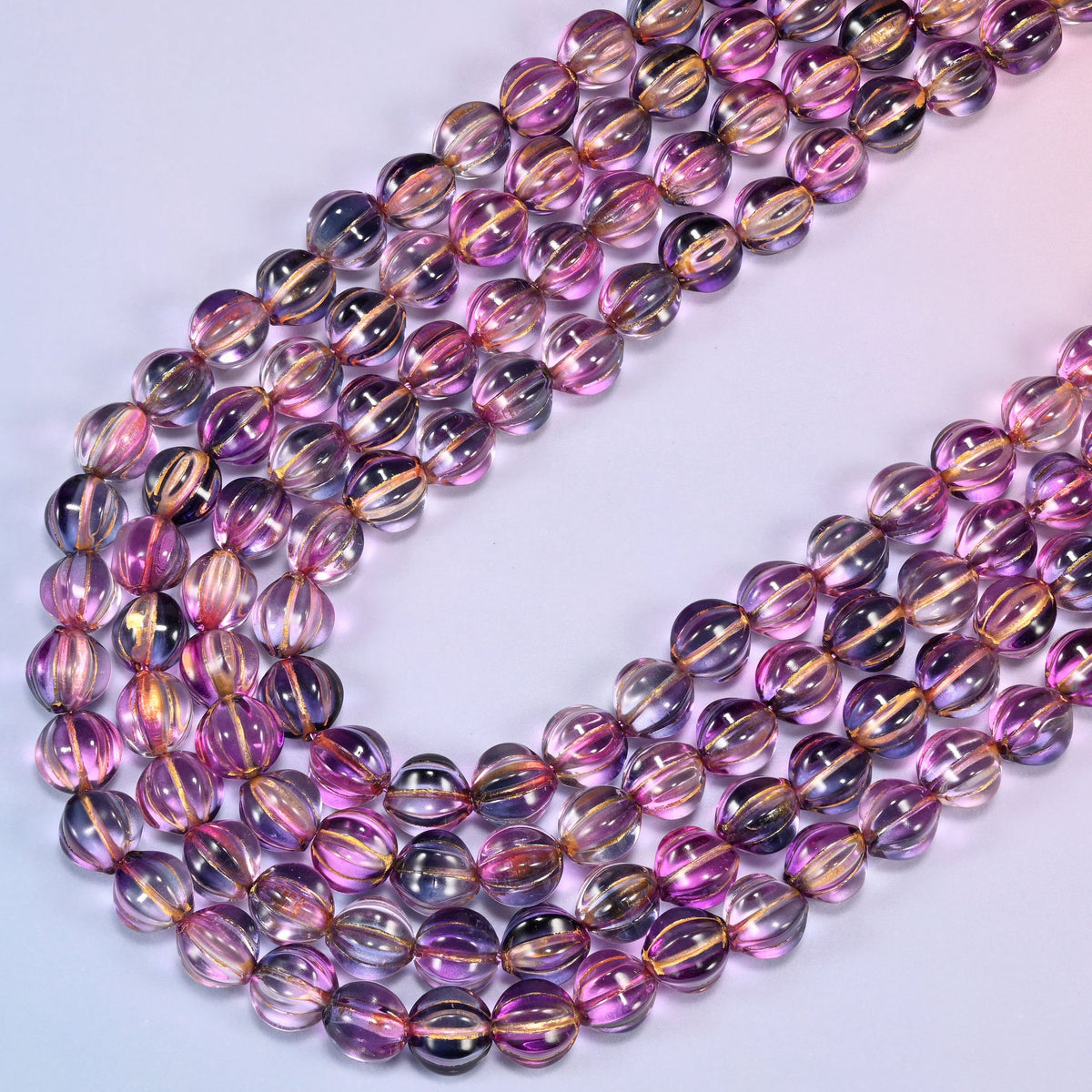 Pink blue gold pumpkin glass beads laid in a narrow chevron, the two limbs running close together down to a point.
