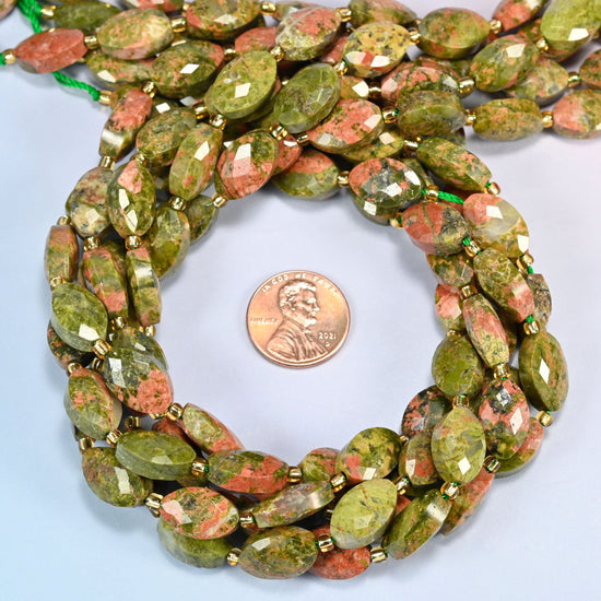Unakite faceted flat oval beads 9x14mm coiled in a loop around a US penny for scale, close-up of the faceted flat oval shape