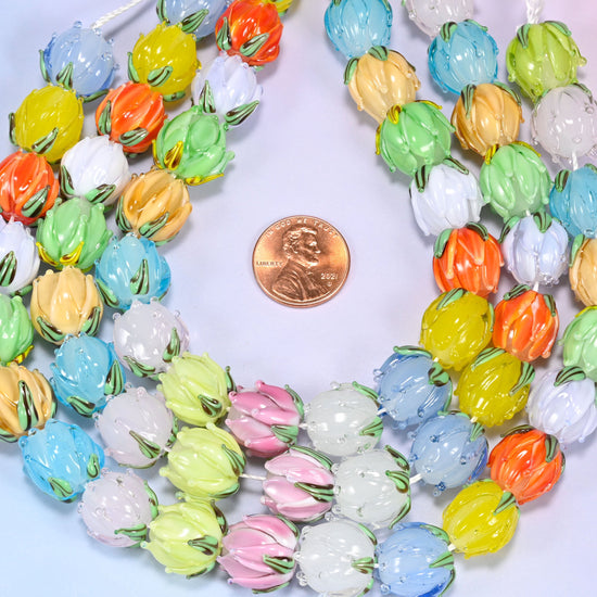 Circular coil of tulip bud lampwork glass bead strands on a lavender background with a penny in the center for size comparison.