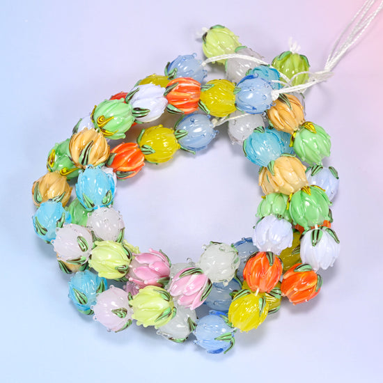 Wide circular coil of multicolor tulip bud lampwork glass beads on a lavender and pink gradient background, showing the full wreath.