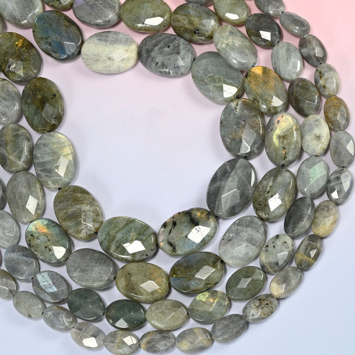 Gray Labradorite faceted oval beads curved into a wide open loop, near-white beads beside dark ones
