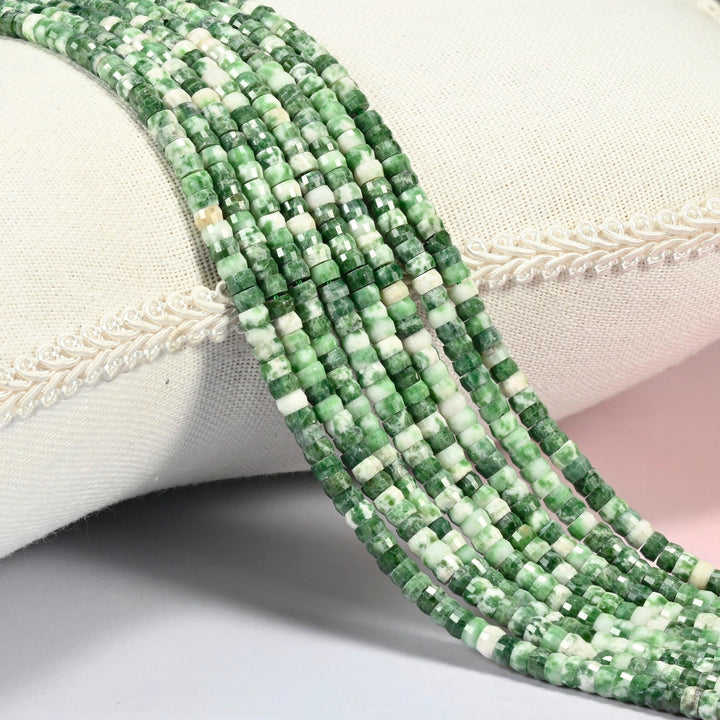 Tree agate faceted heishi disc beads 2x4mm, several strands draped over a white cushion