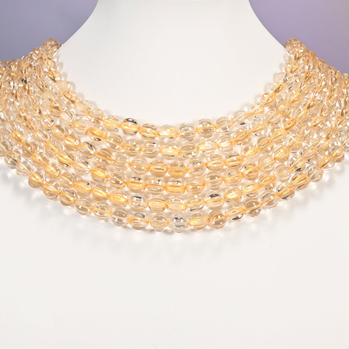 Clear gold pumpkin glass beads shown as layered strands on a white neck display form.
