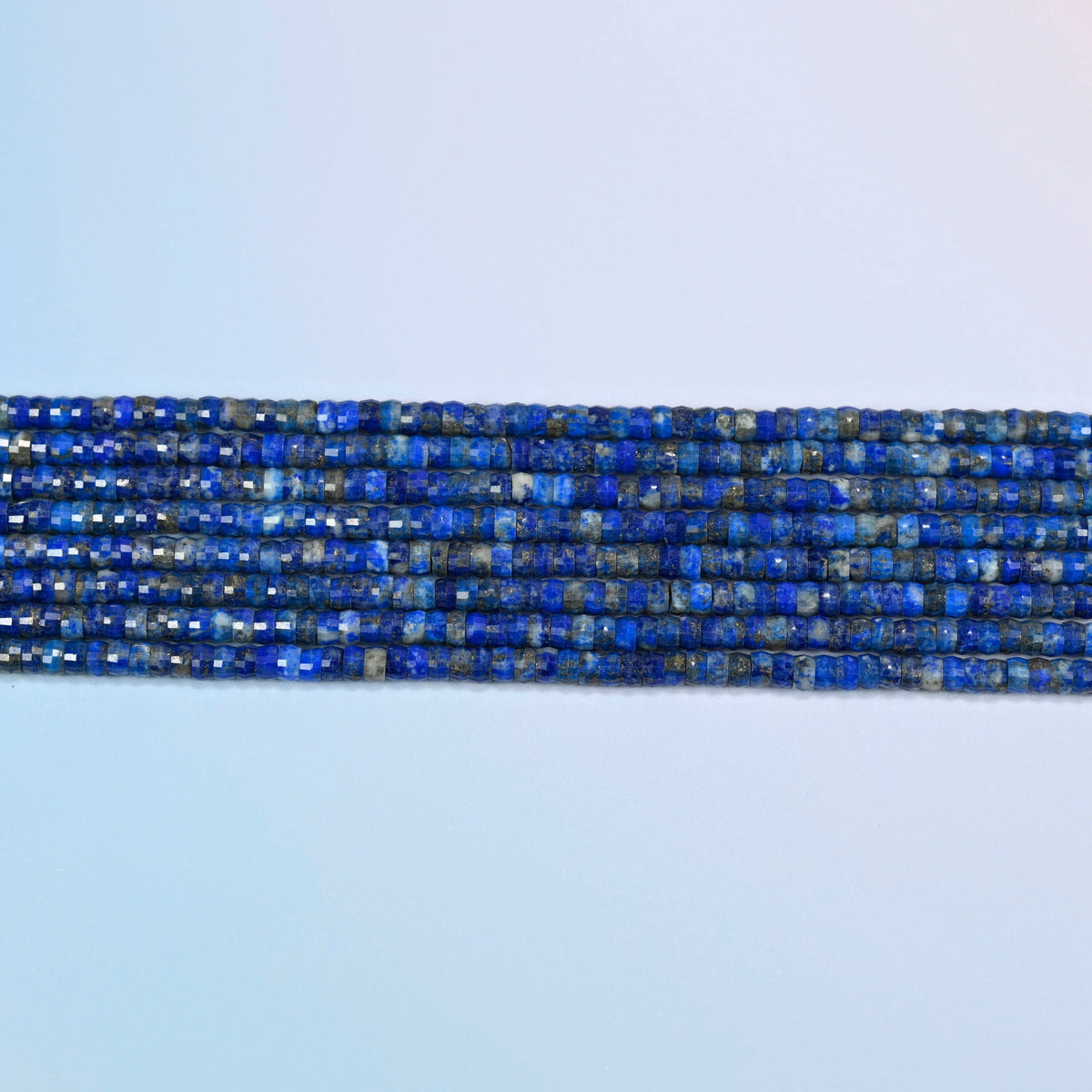 Several strands of lapis faceted heishi disc beads laid in straight rows