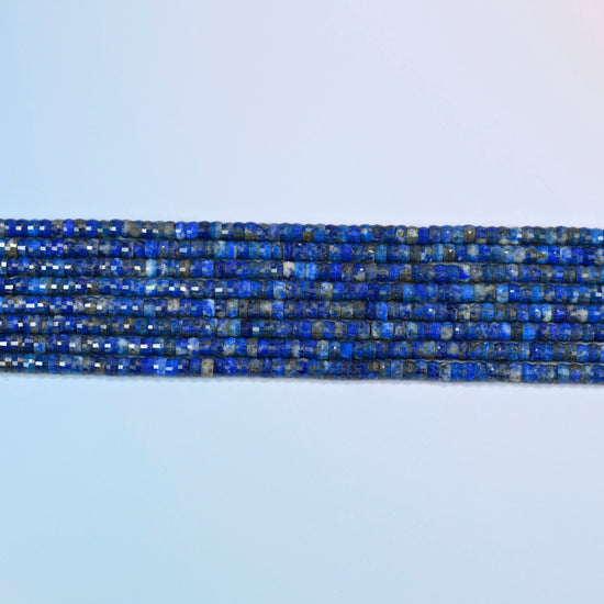 Several strands of lapis faceted heishi disc beads laid in straight rows