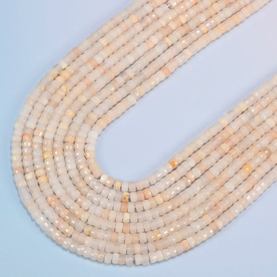 Pink aventurine faceted heishi disc beads in several strands curved into a wide U, light peach pink stone