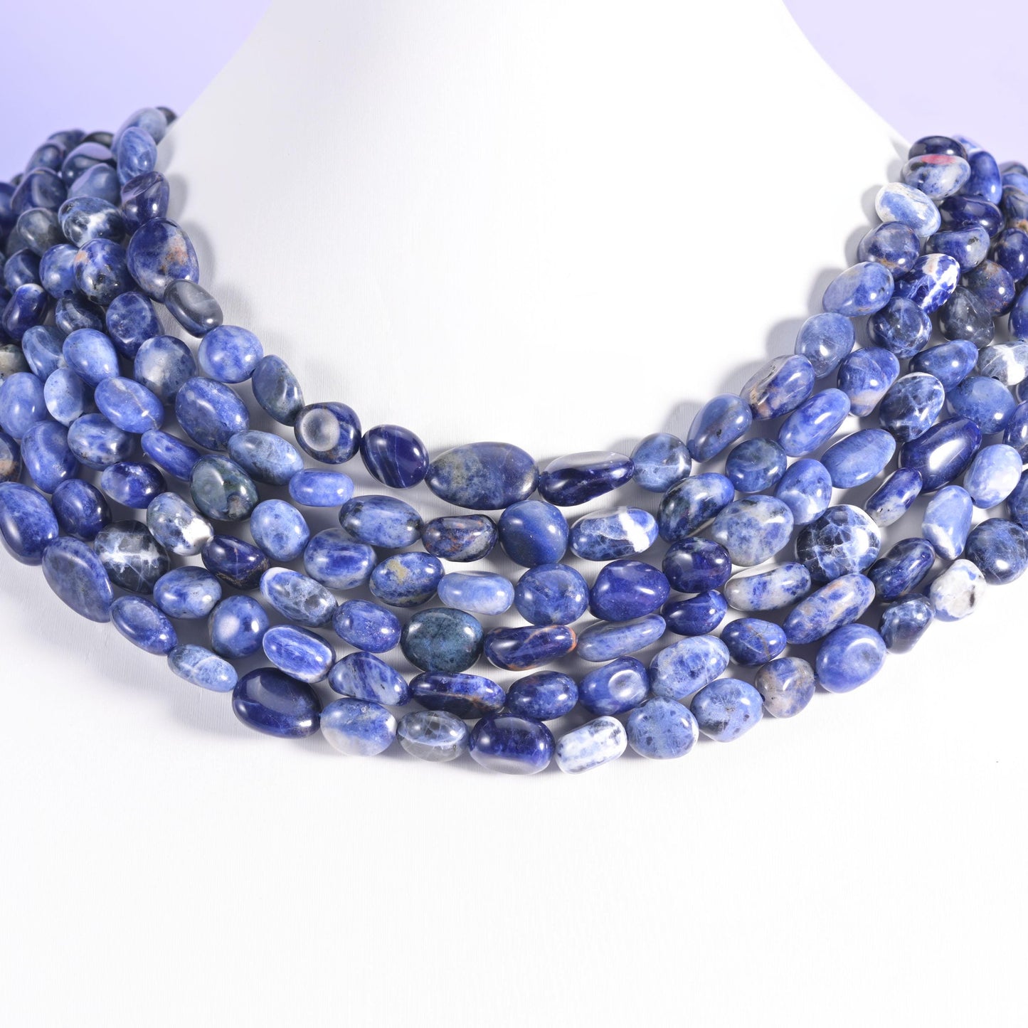 Sodalite pebble nugget strands draped across a white neck display form