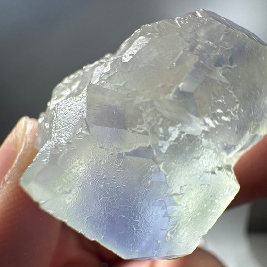 Fluorite specimen backlit in the hand, light passing through the clear crystal