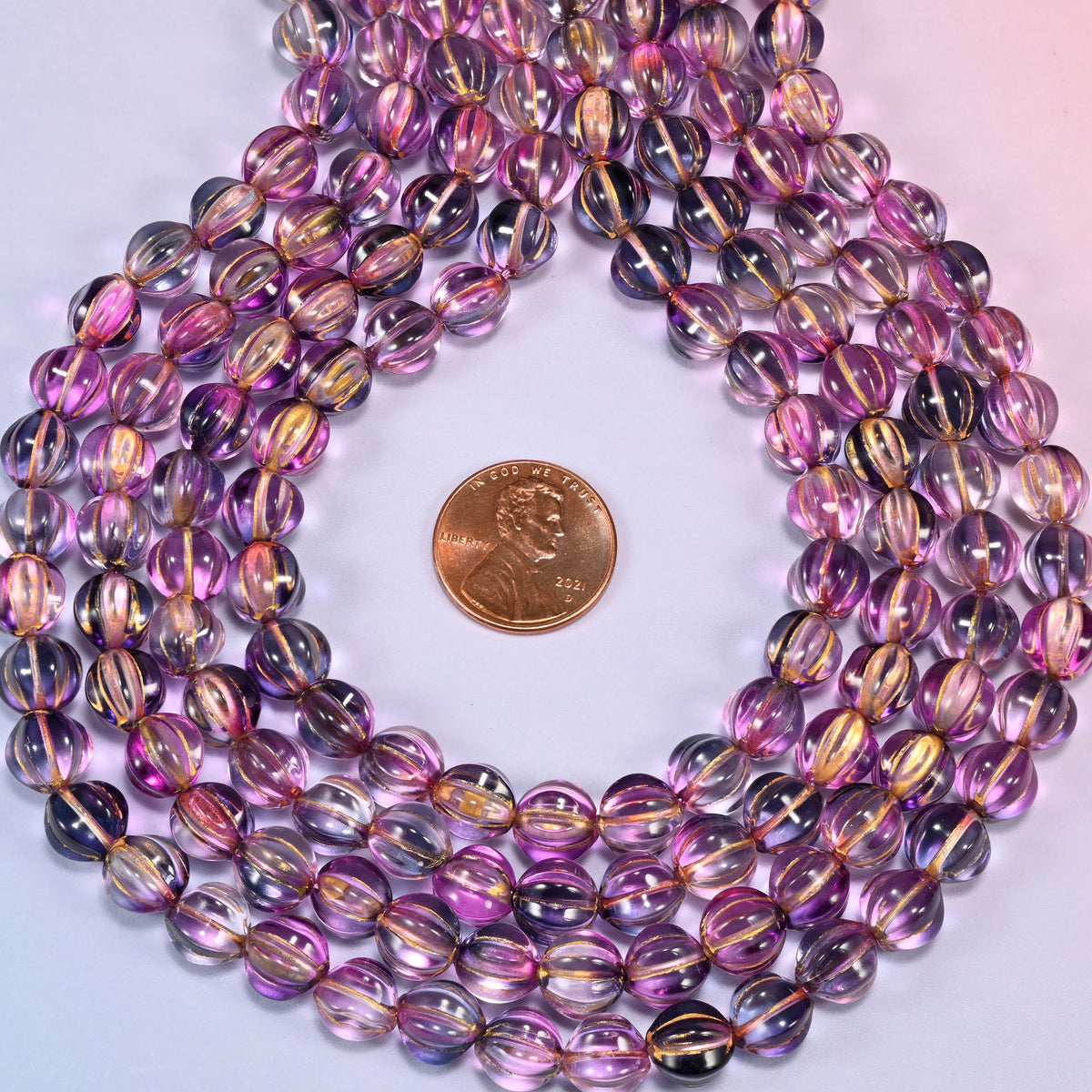 Pink blue gold pumpkin glass beads coiled flat into several concentric rings around an open center.