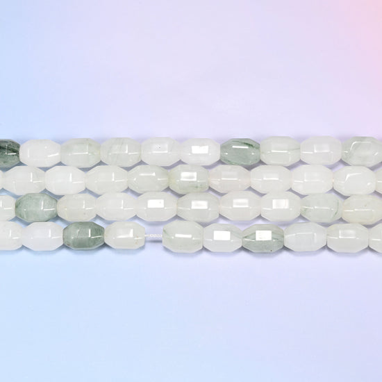 Close-up rows of Tianshan Jade faceted barrel beads laid flat, showing the mostly white and cream tone with sage green marbled beads mixed in.