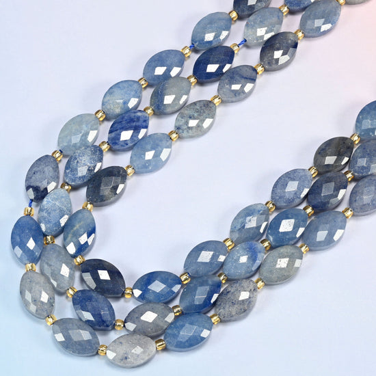 Blue aventurine faceted flat oval beads in several strands curved into a wide U, light to dark blue stone