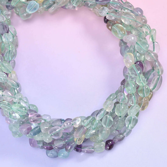 Fluorite nugget strand coiled into a ring on a soft pink backdrop