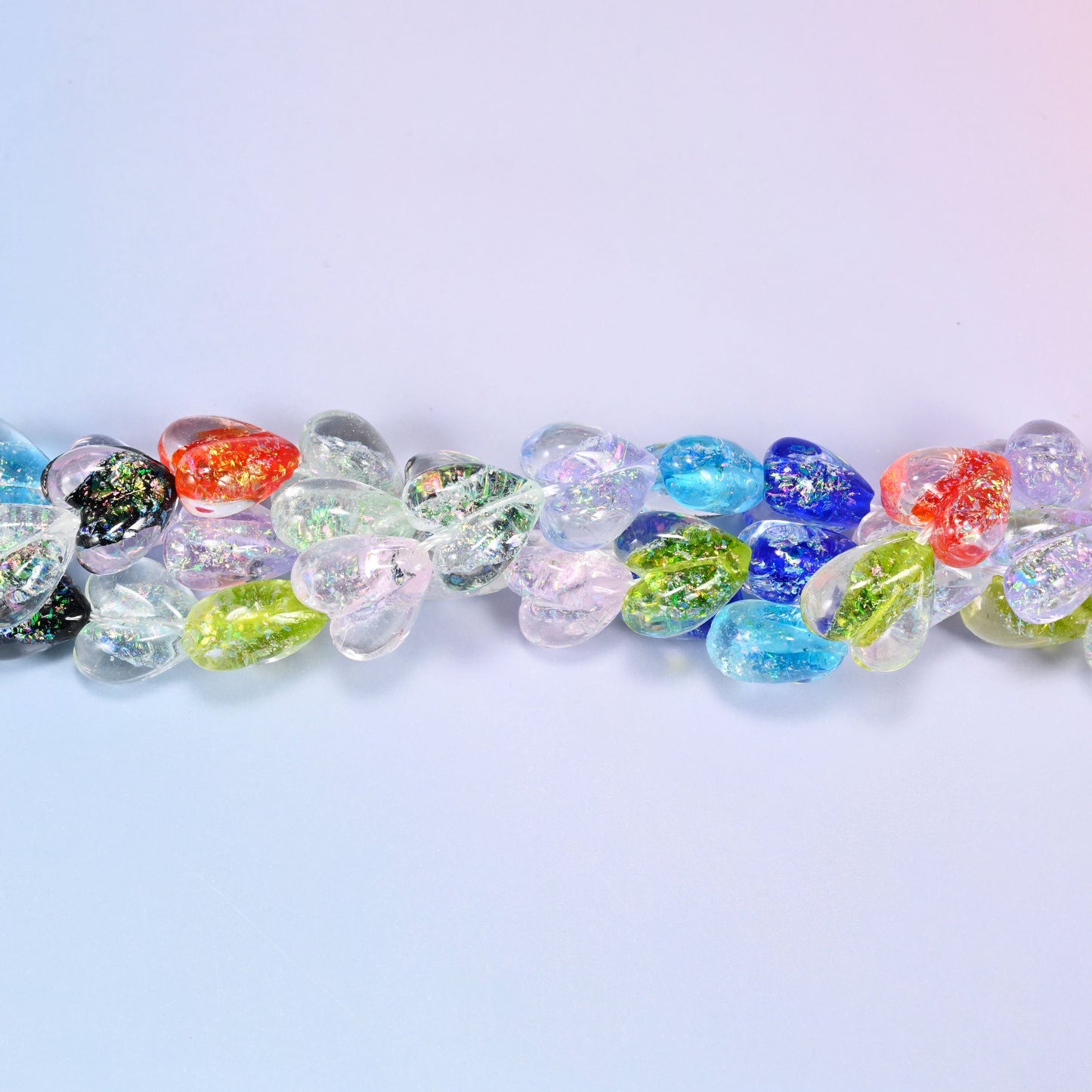 Puffed transparent hearts in a mixed run of clear, ice blue, cobalt, lime, coral red and speckled black with an iridescent coating